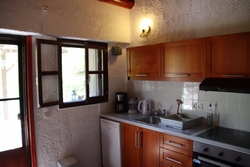 Küche mit Kühlschrank, Ofen mit drei Kochplatten und Einzelbett.